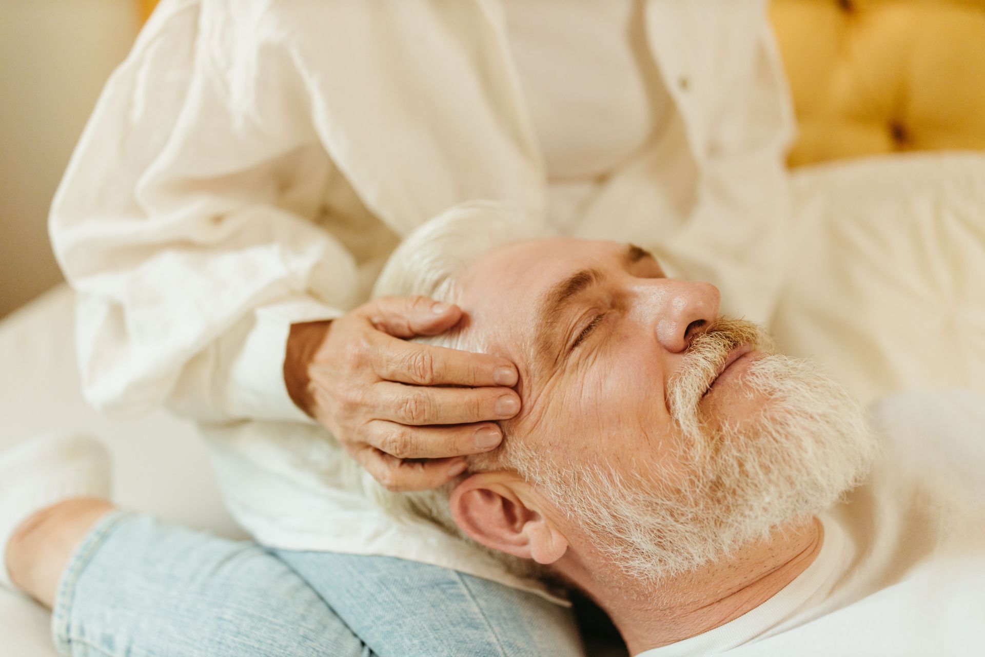 Senior man enjoys a relaxing massage session indoors, highlighting wellness and calm.